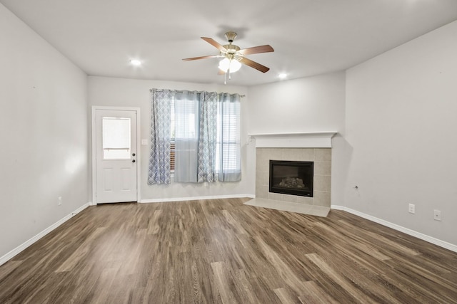 unfurnished living room featuring a tiled fireplace, ceiling fan, and dark hardwood / wood-style floors