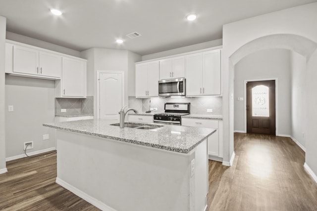 kitchen with appliances with stainless steel finishes, sink, white cabinetry, and an island with sink