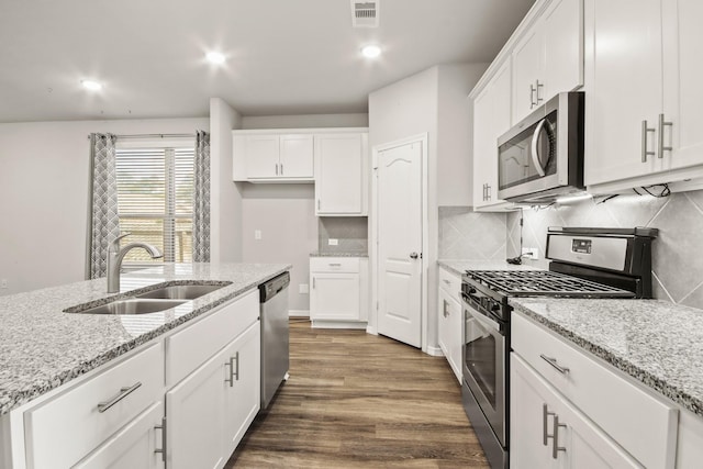 kitchen featuring light stone counters, stainless steel appliances, white cabinetry, and sink