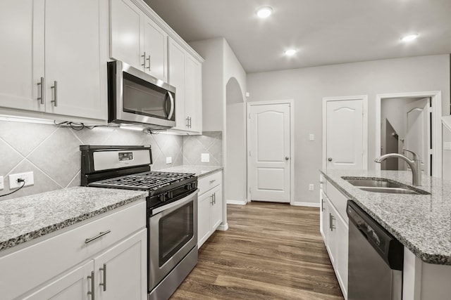 kitchen featuring white cabinets, stainless steel appliances, light stone counters, and sink