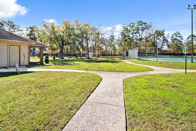 surrounding community featuring tennis court and a yard