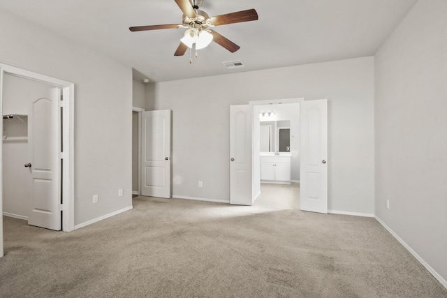 unfurnished bedroom with ensuite bath, a spacious closet, ceiling fan, light colored carpet, and a closet