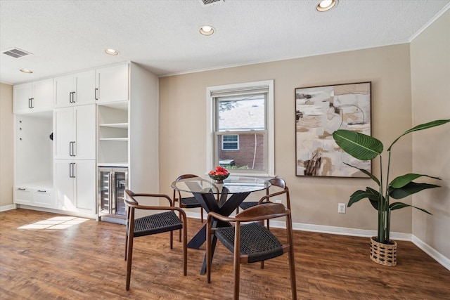 dining room with crown molding, dark wood-type flooring, wine cooler, and a textured ceiling