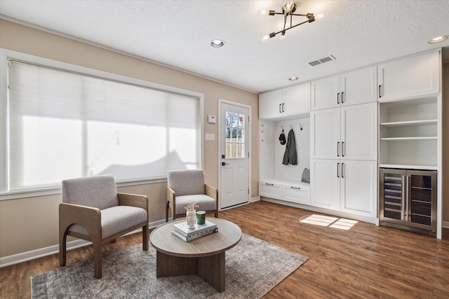 sitting room featuring wine cooler, dark hardwood / wood-style flooring, and a textured ceiling