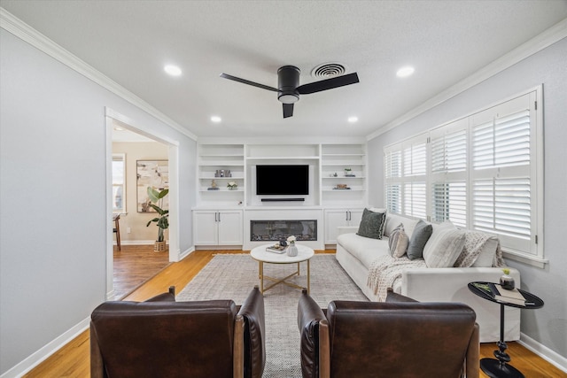 living room featuring light wood-style flooring, baseboards, ceiling fan, and crown molding