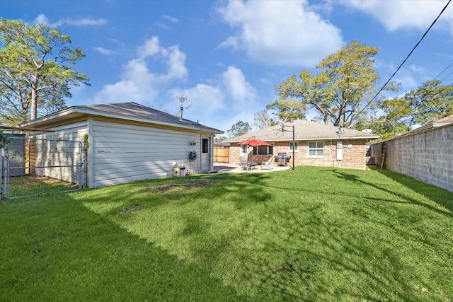 rear view of house with a fenced backyard, a lawn, and a patio