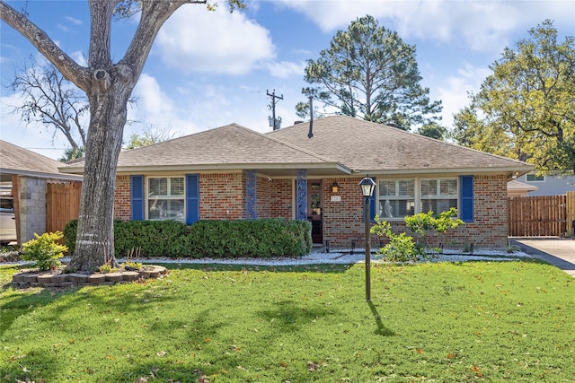 ranch-style home featuring a shingled roof, brick siding, fence, and a front lawn