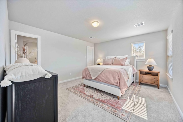 bedroom with light colored carpet and a textured ceiling