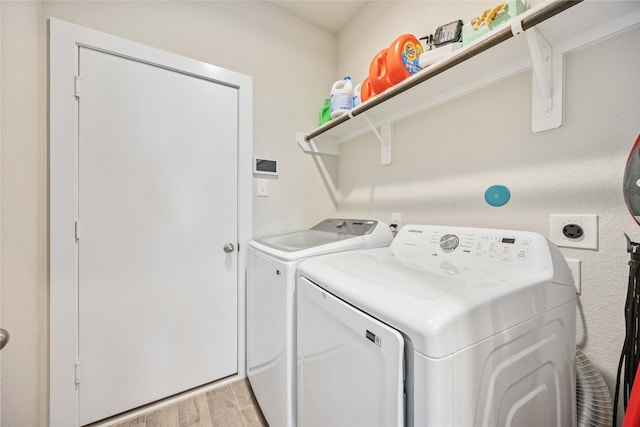 clothes washing area featuring separate washer and dryer and light hardwood / wood-style floors