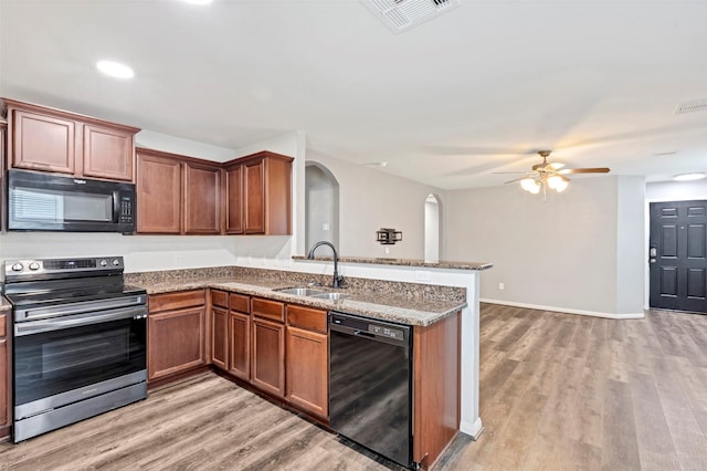 kitchen with ceiling fan, sink, stone counters, kitchen peninsula, and black appliances