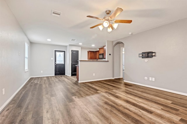 unfurnished living room with ceiling fan and dark wood-type flooring