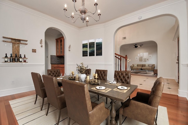 dining area with ceiling fan with notable chandelier, wood-type flooring, and ornamental molding