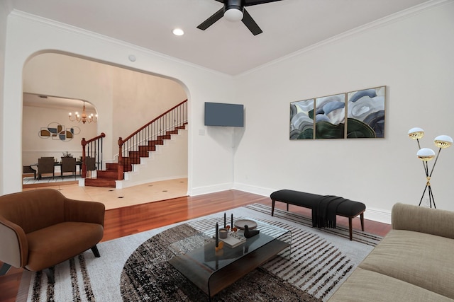 living room with hardwood / wood-style floors, ceiling fan with notable chandelier, and ornamental molding