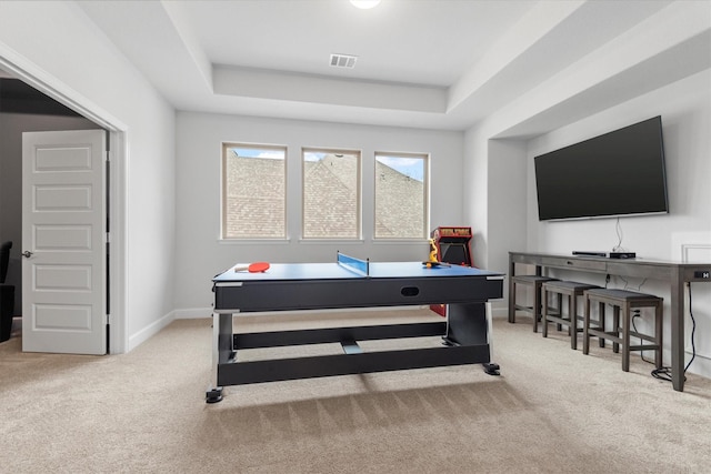 rec room with light colored carpet and a raised ceiling