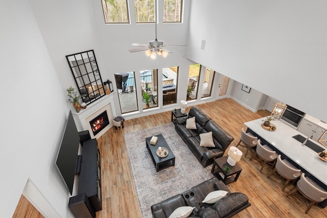 living room with a high ceiling, hardwood / wood-style flooring, ceiling fan, and a healthy amount of sunlight