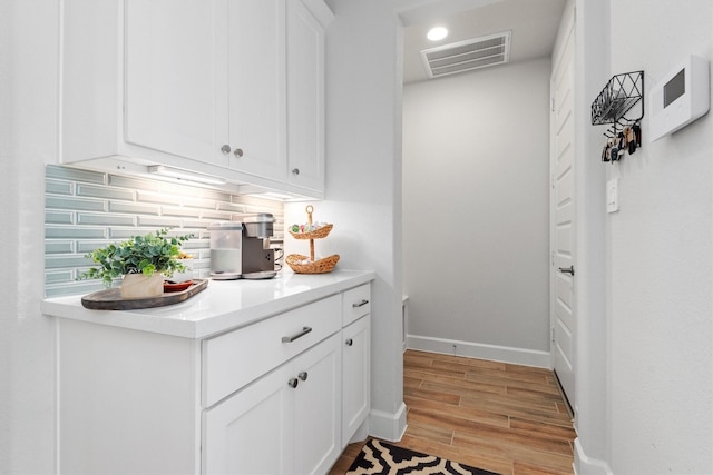 bar featuring white cabinets, tasteful backsplash, and light hardwood / wood-style flooring