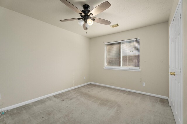 spare room featuring a ceiling fan, baseboards, visible vents, and light carpet