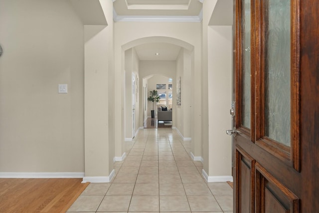 hall with light tile patterned floors, baseboards, and arched walkways