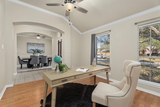 office with baseboards, light wood-type flooring, vaulted ceiling, ornamental molding, and arched walkways