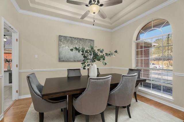 dining room featuring a ceiling fan, light wood-style floors, and a tray ceiling