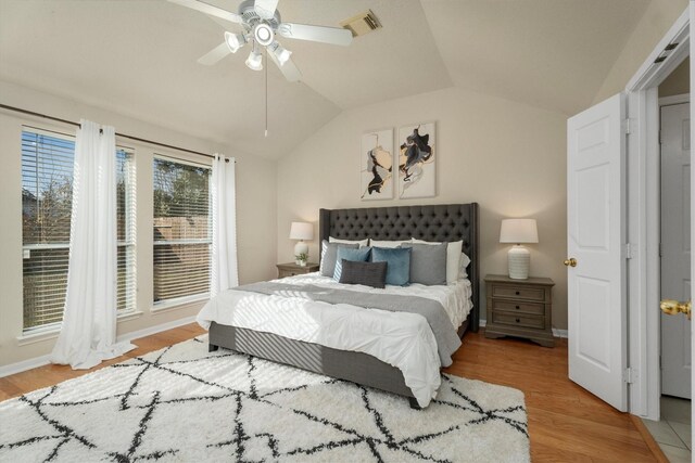 bedroom featuring visible vents, wood finished floors, baseboards, and vaulted ceiling