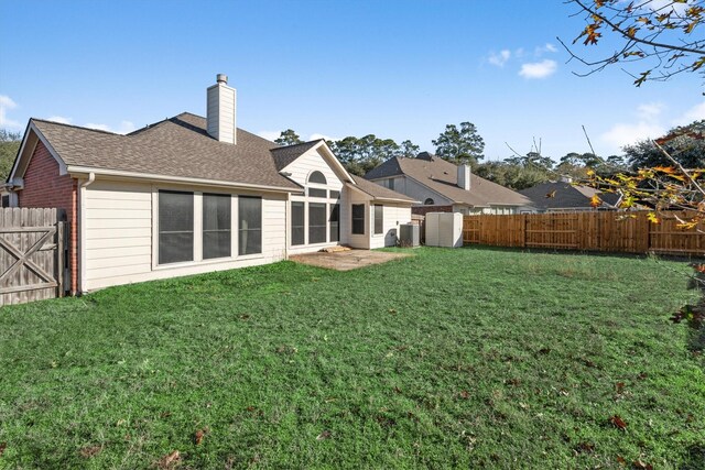 back of property with a shingled roof, a lawn, a fenced backyard, and a chimney