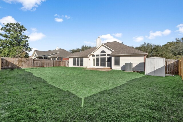 rear view of house featuring a yard, central AC, a fenced backyard, and a chimney