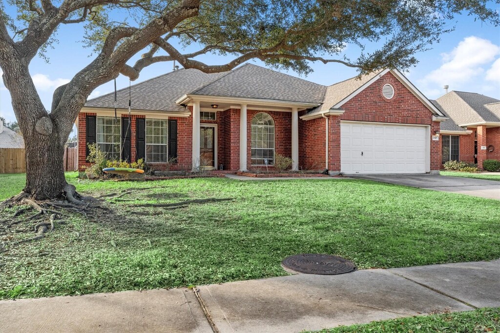 22985 Woodside Estates Ln, Conroe, TX 77385 - single story home with concrete driveway, fence, a front lawn, brick siding, and a garage