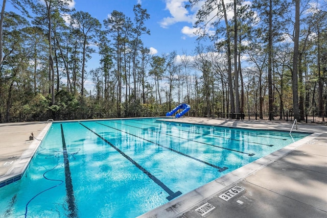 community pool with fence and a water slide