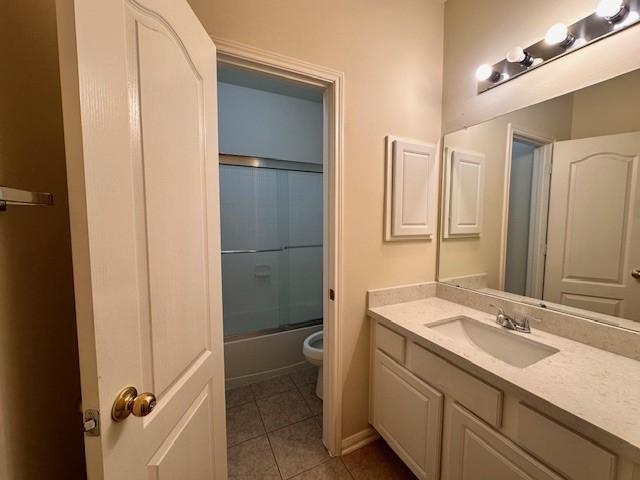 full bathroom featuring shower / bath combination with glass door, tile patterned floors, vanity, and toilet