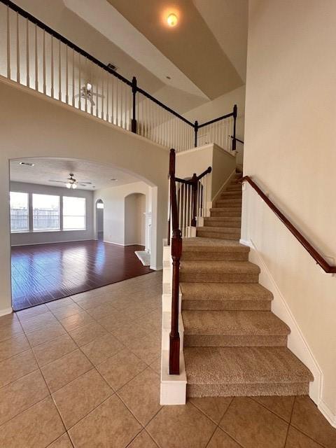 staircase with tile patterned floors and ceiling fan