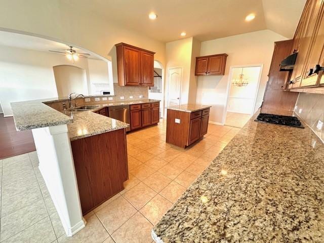 kitchen featuring ceiling fan, sink, backsplash, a kitchen island, and appliances with stainless steel finishes