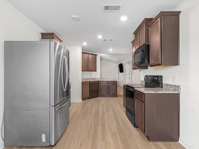 kitchen featuring black appliances, sink, light wood-type flooring, light stone counters, and dark brown cabinetry