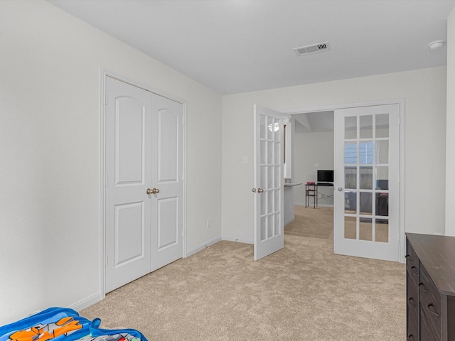 interior space with a closet, light carpet, and french doors