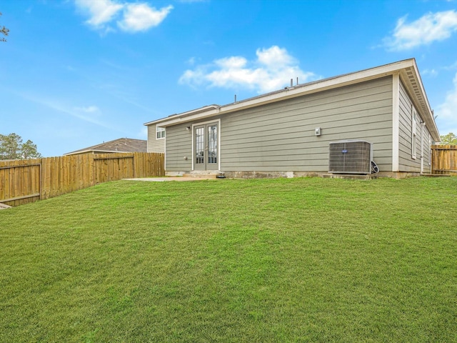 rear view of house with a lawn, central AC, and french doors