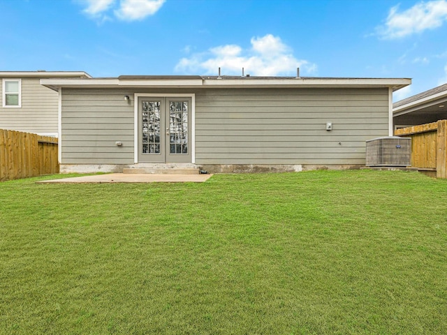 rear view of house with central AC and a lawn