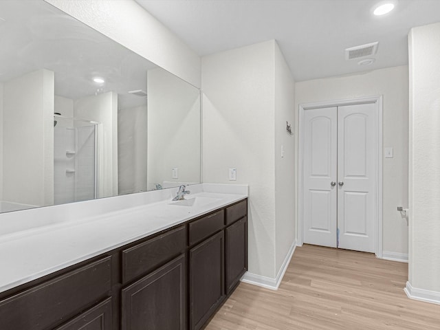 bathroom featuring vanity, wood-type flooring, and a shower with door