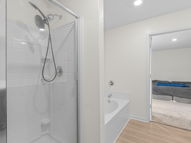 bathroom featuring plus walk in shower and hardwood / wood-style flooring