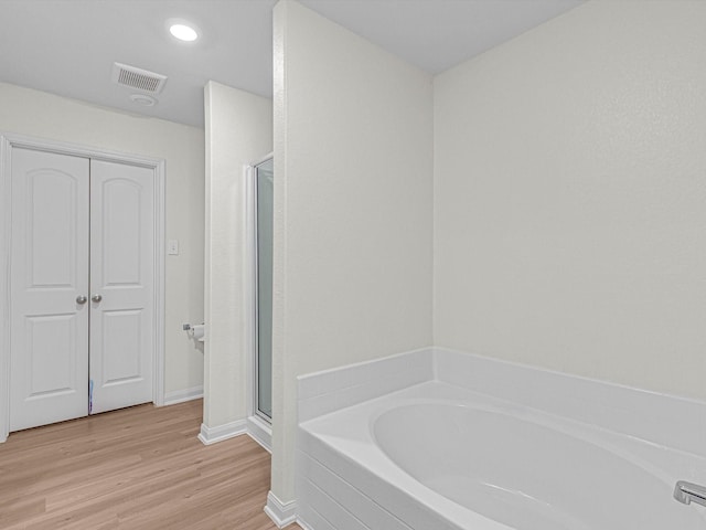 bathroom with shower with separate bathtub and wood-type flooring