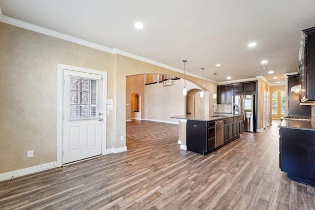 kitchen with hardwood / wood-style floors, stainless steel fridge with ice dispenser, hanging light fixtures, and a kitchen island with sink