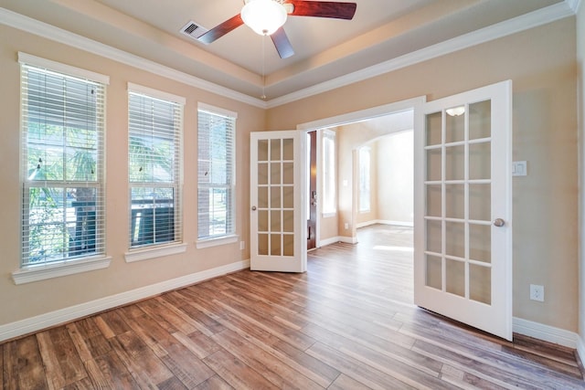 spare room with french doors, light hardwood / wood-style floors, a raised ceiling, and ceiling fan