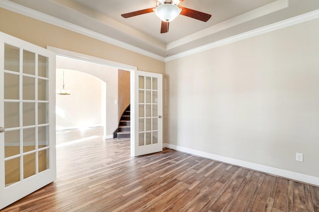 spare room featuring ceiling fan, french doors, a raised ceiling, crown molding, and hardwood / wood-style floors