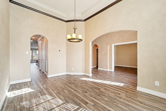 empty room featuring hardwood / wood-style flooring, ornamental molding, and a notable chandelier