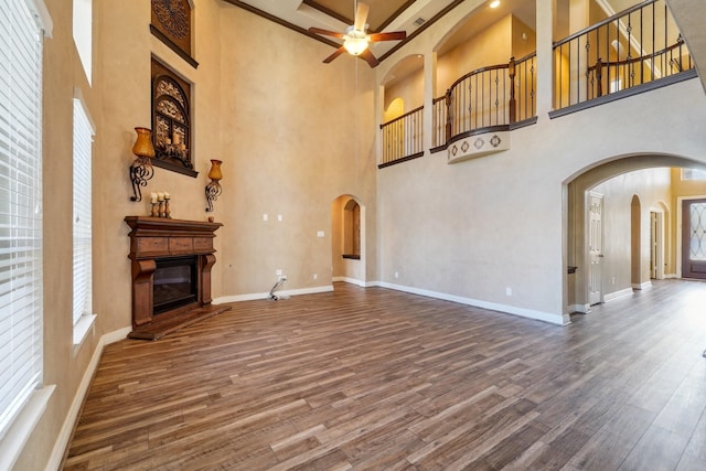 unfurnished living room with a high ceiling, hardwood / wood-style flooring, and ceiling fan