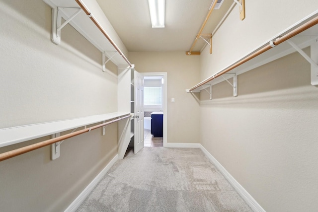 walk in closet featuring light carpet