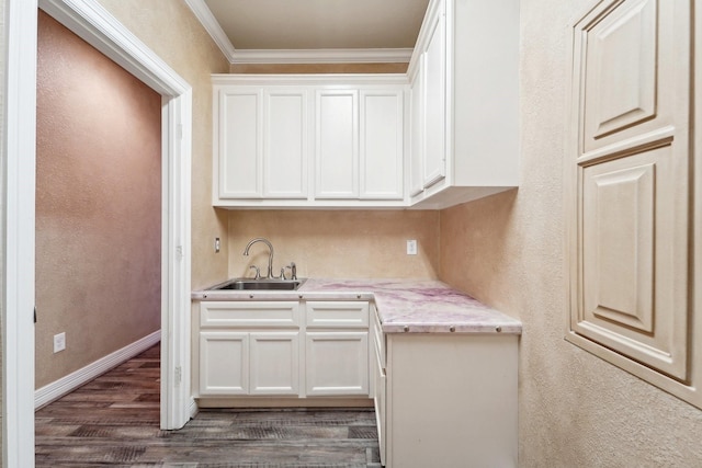 kitchen with white cabinets, dark hardwood / wood-style floors, ornamental molding, and sink