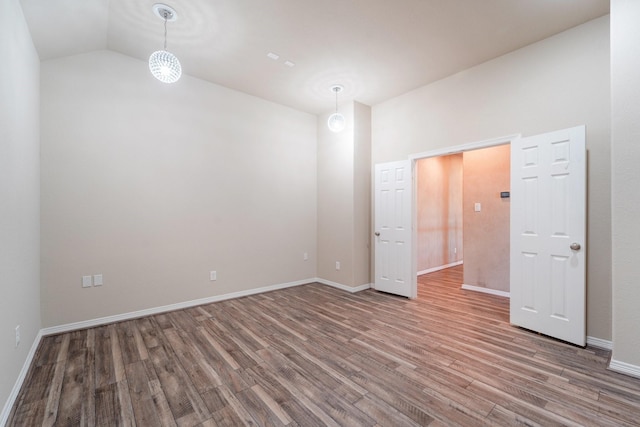 unfurnished room with hardwood / wood-style floors and lofted ceiling