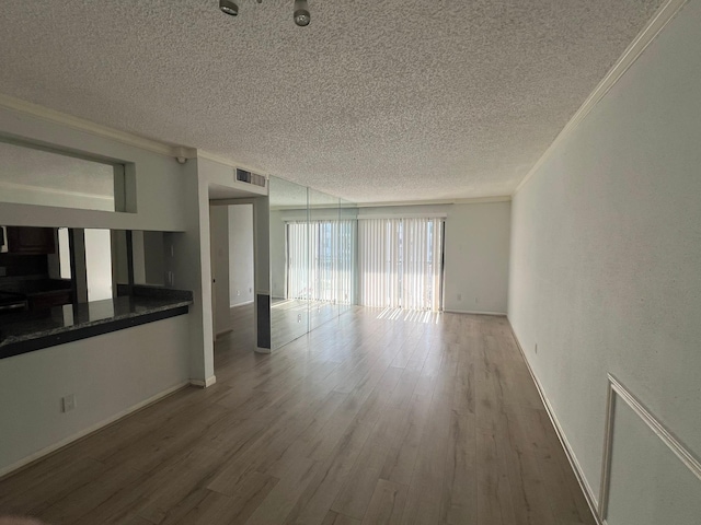 empty room with hardwood / wood-style flooring, ornamental molding, and a textured ceiling