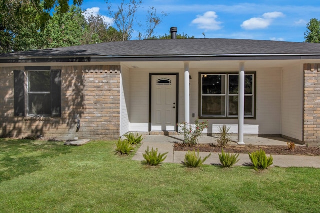 entrance to property featuring a lawn and covered porch