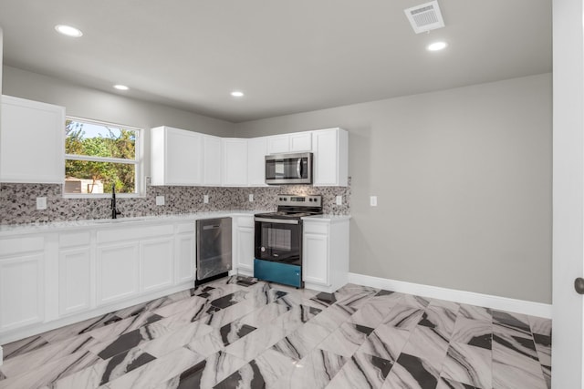 kitchen with backsplash, white cabinets, and appliances with stainless steel finishes